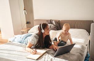 Showing laptop. Mother with her little son is at home in domestic room photo