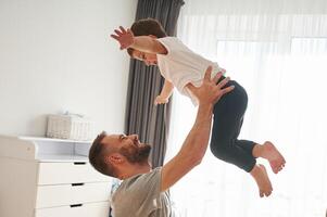 Playing, holding ,in ,,,hands. Man is playing with his little son in the domestic room photo