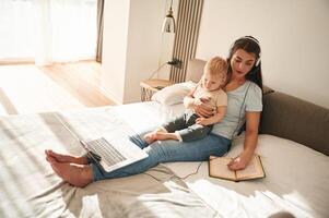 On the comfortable bed. Mother, with, her little son is at home in domestic room photo