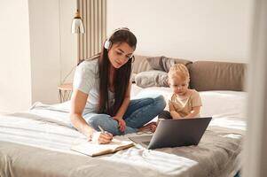 Showing laptop. Mother with her little ,son is at home in domestic room photo