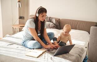 Showing,, laptop. Mother with her little son is at home in domestic room photo