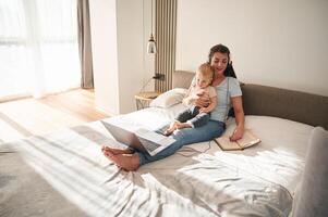 On the comfortable bed. Mother ,with her little son is at home in domestic room photo