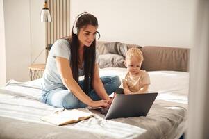 Showing laptop. Mother, with her little son is at home in domestic room photo