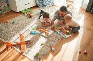Enjoying ,board, game. Father is playing with two little boys on the floor with toys photo