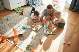 Enjoying, board game. Father is playing with two little boys on the floor with toys photo