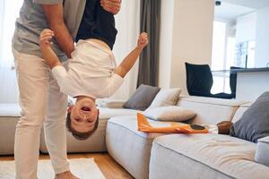 Holding, kid upside down. Man is playing with his little son in the domestic room photo