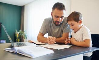 Writing, the homework. Father and son are at home by the table photo