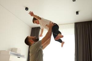 Boy, is imagining that he, is flying. Father holding him. Man is playing with his little son in the domestic room photo