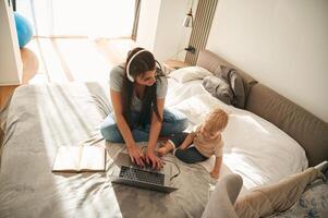 Showing, laptop. Mother with her little son is at home in domestic room photo