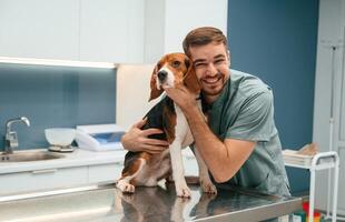 Playful mood, having fun. Dog in veterinarian clinic with male doctor photo