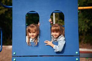 Hiding behind blue construction, smiling... Kids are having fun on the playground photo