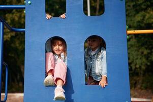 Hiding, behind ,blue, construction, smiling. Kids are having fun on the playground photo