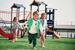 Holding soccer ball in hand, running... Kids are having fun on the playground photo