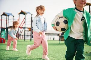 Holding ,soccer ball in hand, ,,running. Kids are having fun on the playground photo
