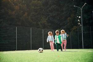 Running with ball. Kids are having fun on the green soccer field together photo