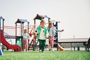 Holding, soccer ball in hand, running.. Kids are having fun on the playground photo