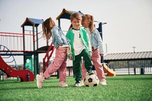 With soccer ball. Kids are having fun on the playground photo