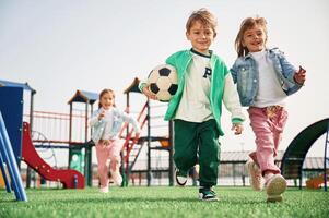 Holding soccer ball in hand,. running. Kids are having fun on the playground photo