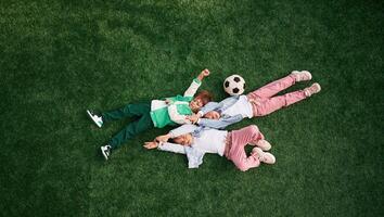 Lying down. Kids are having fun on the green soccer field together photo