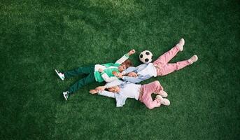 Top view. Lying down. Kids are having fun on the green soccer field together photo