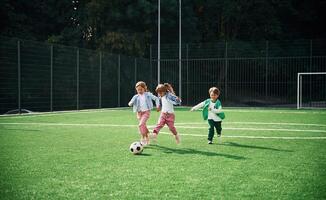 Running ,with ,ball. Kids are having fun on the green soccer field together photo