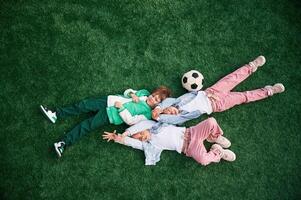 Top view. Lying down. Kids are having, fun ,on the green soccer field together photo