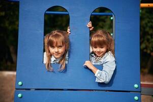 Hiding behind blue construction, ,smiling. Kids are having fun on the playground photo