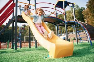 On the playground slide.,, Kids are,, having fun photo