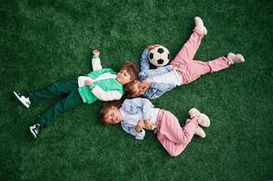 Top view. Lying down. Kids are having fun, on the green soccer field together photo