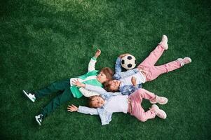 Top view. Lying down. Kids are, having fun on the green soccer field together photo