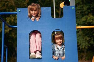 Hiding behind blue construction, smiling,. Kids are having fun on the playground photo