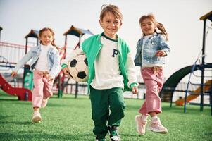 Holding, soccer ,ball in hand, running. Kids are having fun on the playground photo