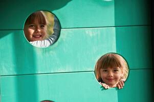 Looking through two holes, smiling. Kids are having fun on the playground photo