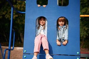 Hiding behind, blue construction, smiling. Kids are having fun on the playground photo