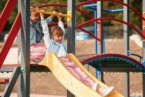 On ,a playground slide. Little girl is having fun on photo