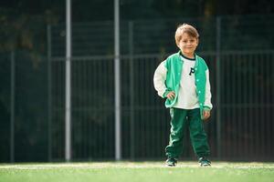 Full height, photo of little boy on green field