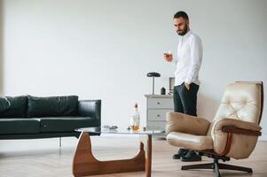 Walking and drinking whiskey. Upset young man alcoholic ,,is, indoors photo