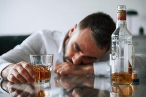 Conception of addiction. Upset,, young man drinker alcoholic is indoors photo
