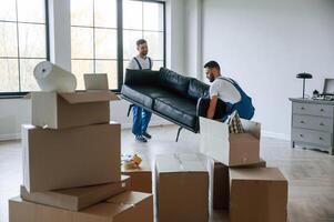 Sofa in hands. Two moving service employees in a ,,room photo