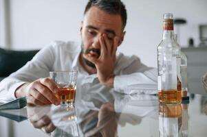 Conception ,of ,addiction. Upset young man drinker alcoholic is indoors photo