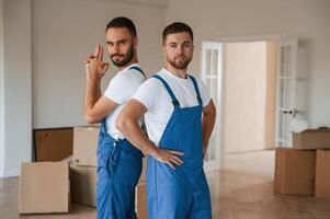 Standing and posing. Two moving service,, employees in a room photo