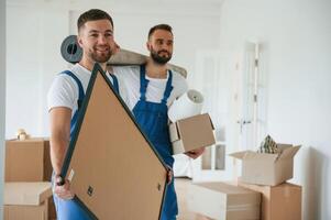 Painting and mat in hands. Two moving, service employees in a room photo