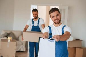 Sign in the documents. Two, moving, service employees in a room photo