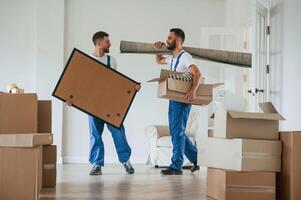 Painting and mat, in ,hands. Two moving service employees in a room photo