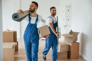 Mat and painting, in, hands. Two moving service employees in a room photo