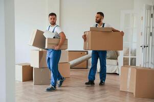 Boxes in hands. ..Two moving service employees in a room photo
