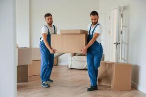 One big heavy box. Two, moving ,service employees in a room photo