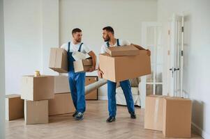 Boxes in hands. Two moving service, employees in a room photo