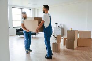 One big,, heavy box. Two moving service employees in a room photo