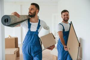 Mat and ,painting, in hands. Two moving service employees in a room photo